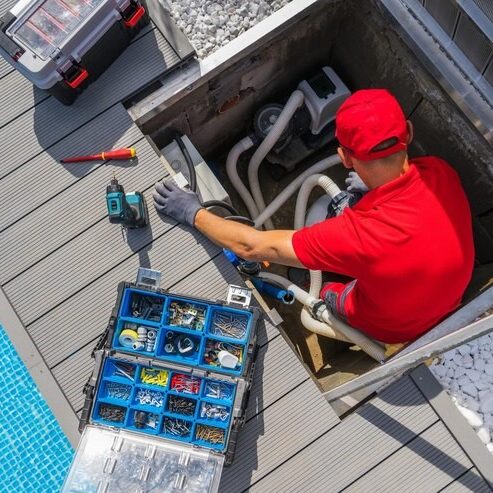 A man working on an outdoor pool deck.